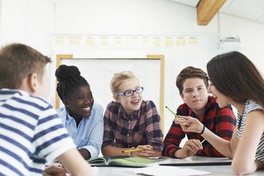 Group Of Teenage Students Collaborating On Project In Classroom